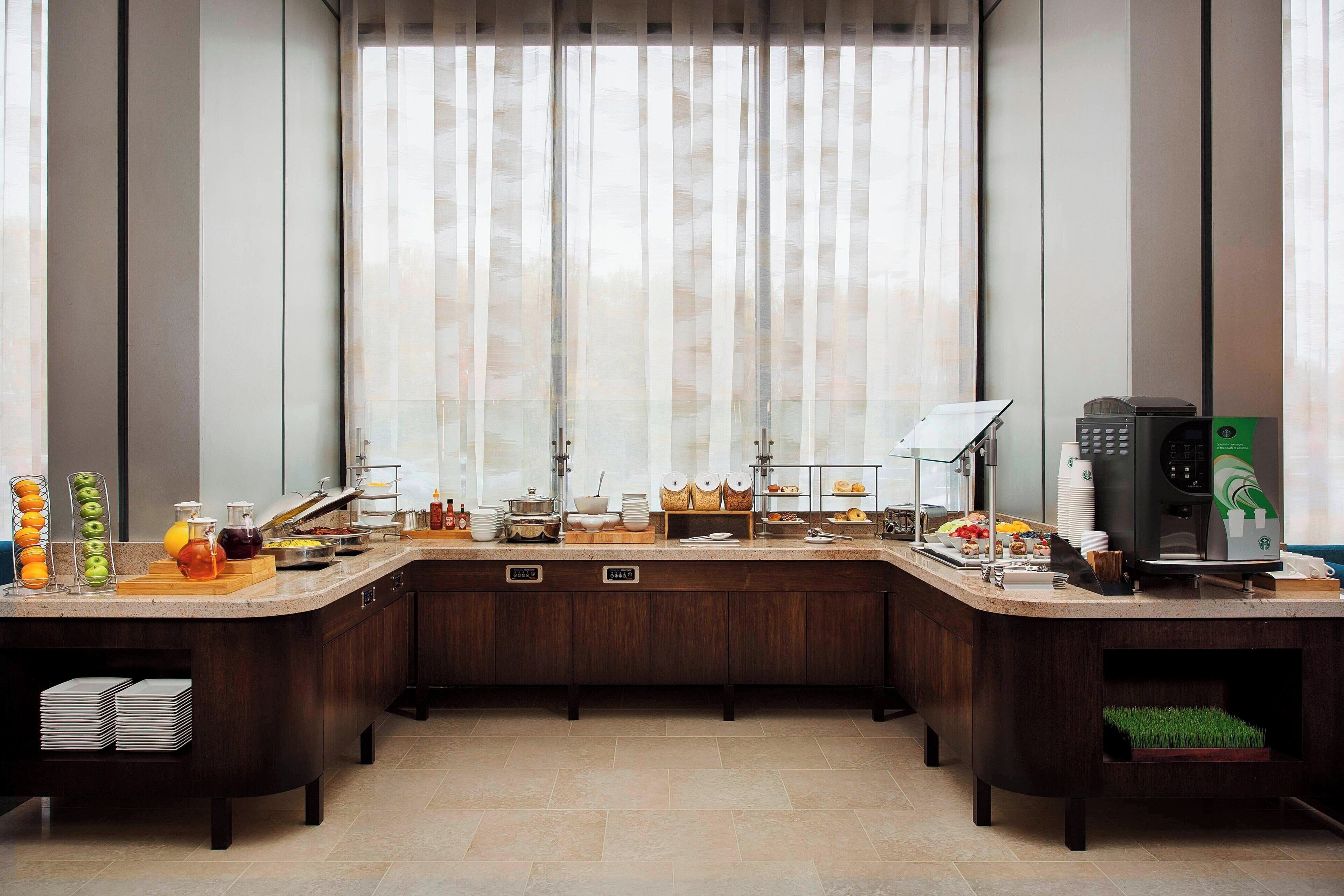 A modern kitchen with a breakfast bar, a coffee machine, and various food items.