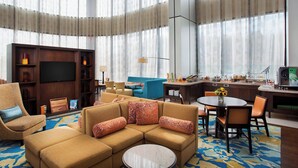 Un hall d’hôtel moderne doté d’un grand espace salon, d’une cuisine et d’un téléviseur.