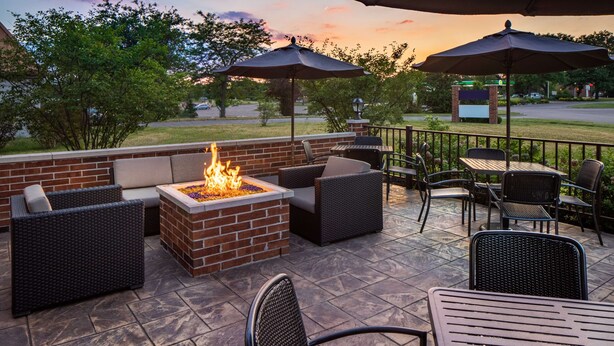 Une terrasse extérieure avec un foyer, des sièges et des parasols.