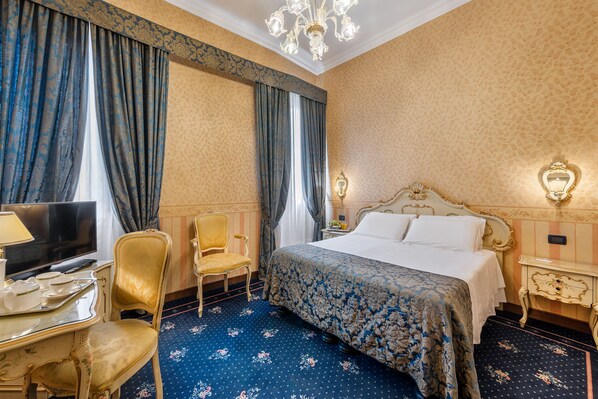 A hotel room with a bed, a television, a chair, and a desk with a lamp. - Hotel Montecarlo (Venice)