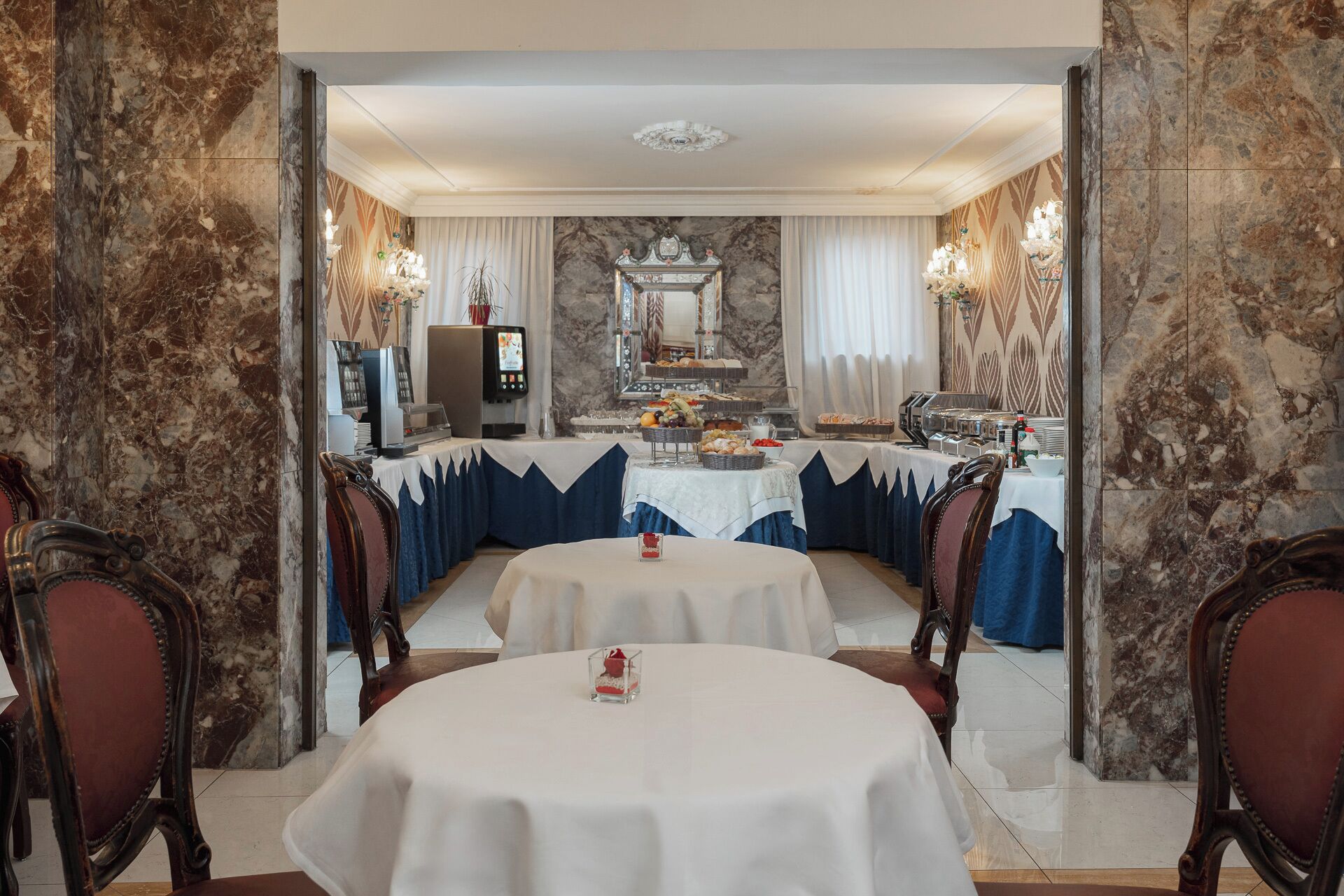 A formal dining room with marble walls, a buffet setup, and classic furniture.
