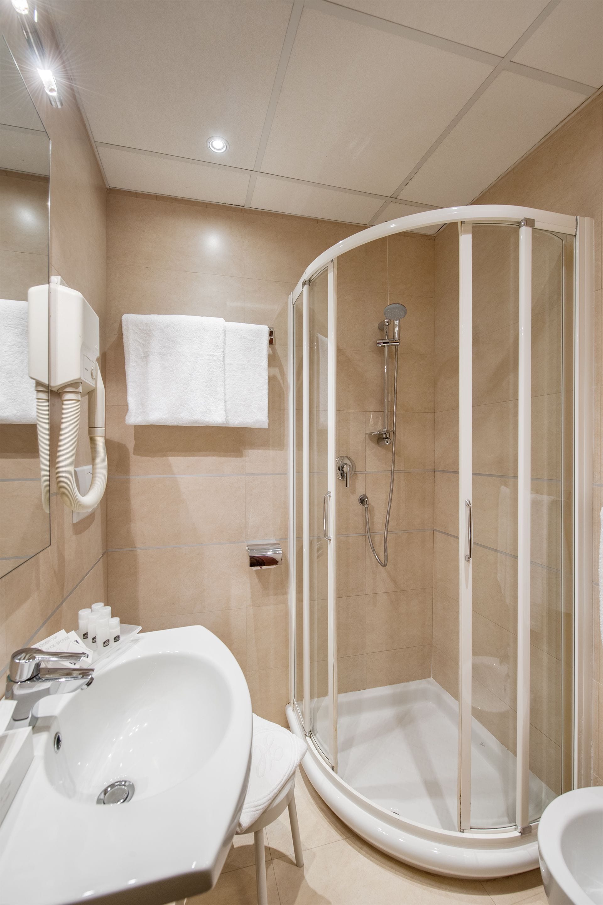Un baño moderno con ducha de vidrio, lavabo blanco y espejo.