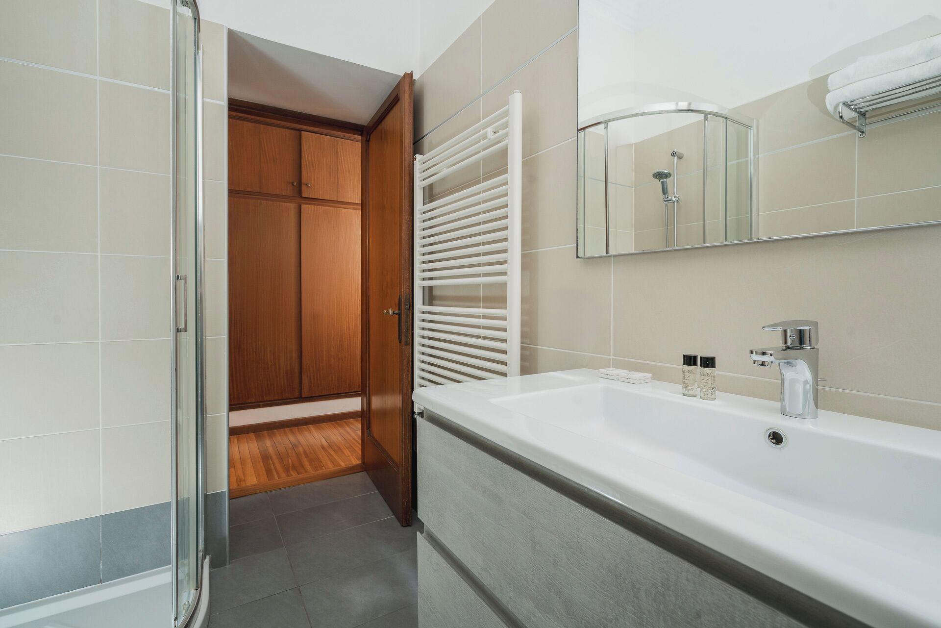 A modern bathroom with a large white sink, a glass shower enclosure, and wooden cabinets.