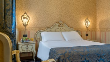 A hotel room with a bed, a nightstand with a fruit bowl and a lamp, and a chair.