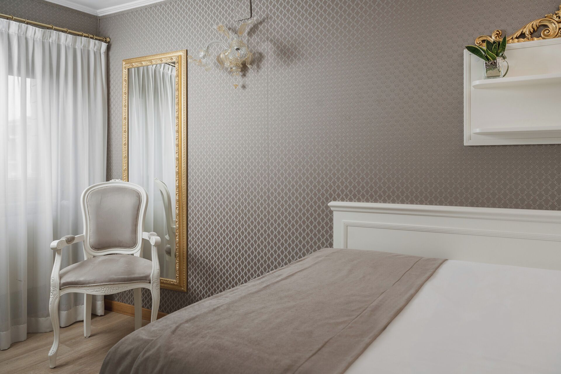 Une chambre à coucher comprenant un lit, une chaise, un miroir et une étagère fixée au mur.