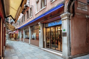A hotel facade with a blue awning, large glass windows displaying interior decor, and a sign reading "Hotel Montecarlo". - Hotel Montecarlo (Venice)