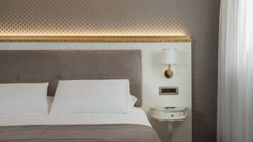 Une chambre d’hôtel avec un grand lit, une table de chevet, une lampe fixée au mur et un papier peint à motifs.