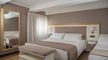 A hotel room with a large bed, a bedside table with a lamp, a mirror, and a window with curtains.