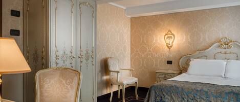 Une chambre d’hôtel comprenant un lit, une chaise, une armoire et une table de chevet avec une lampe.