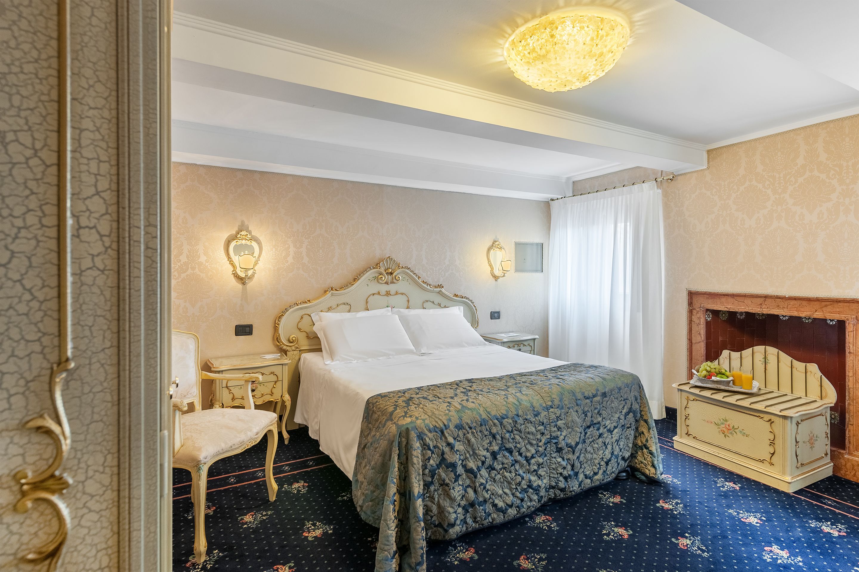 A bedroom with a large bed, a chair, a dresser, and a fireplace.