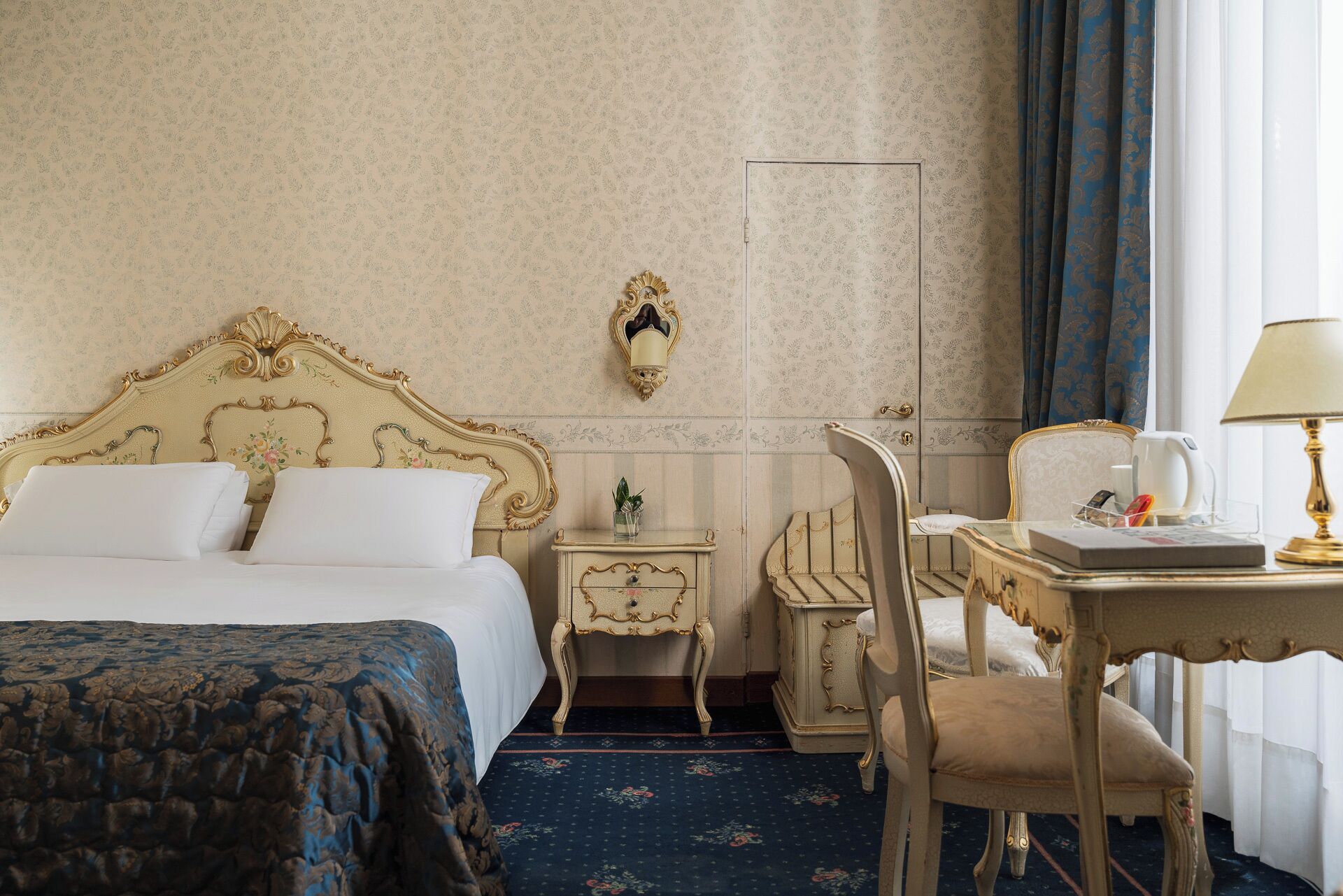 Una habitación de hotel con una cama grande, un escritorio con lámpara y una silla.
