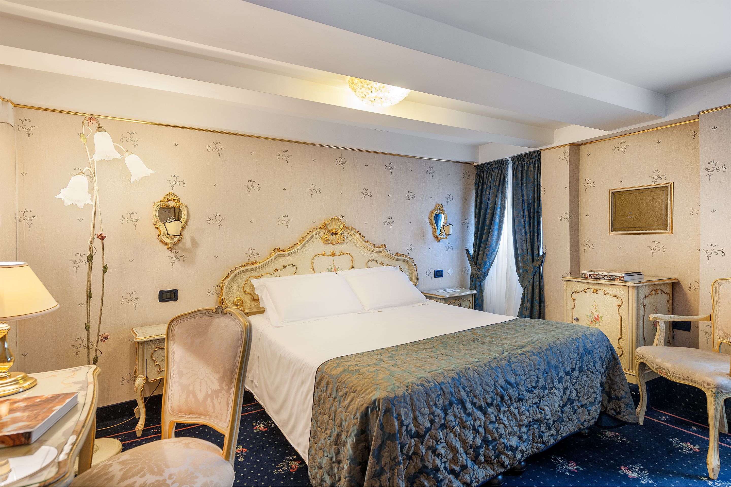 Ein Hotelzimmer mit einem großen Bett, einem Sessel, einem Schreibtisch und einem Spiegel.