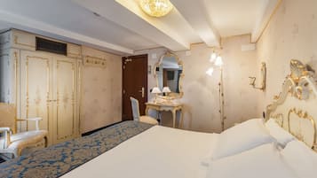 Une chambre d’hôtel avec un grand lit, un bureau avec une lampe, une chaise, une armoire et un miroir.