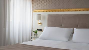 A hotel room with a large bed, a nightstand with a lamp, and a patterned wallpaper.