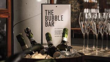 A bar area with a sign reading 'THE BUBBLE BAR' and several champagne bottles and glasses.
