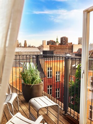 A balcony with a potted plant, two chairs, and a view of city buildings. - Boutique Hotel SP34 (Copenhagen)