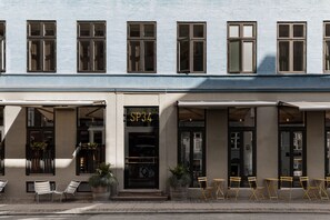 A building with a row of windows, a door labeled 'SP34', outdoor seating, and potted plants. - Boutique Hotel SP34 (Copenhagen)