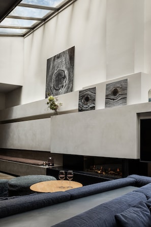 A modern living room with a fireplace, blue sofas, and abstract wall art. - Boutique Hotel SP34 (Copenhagen)