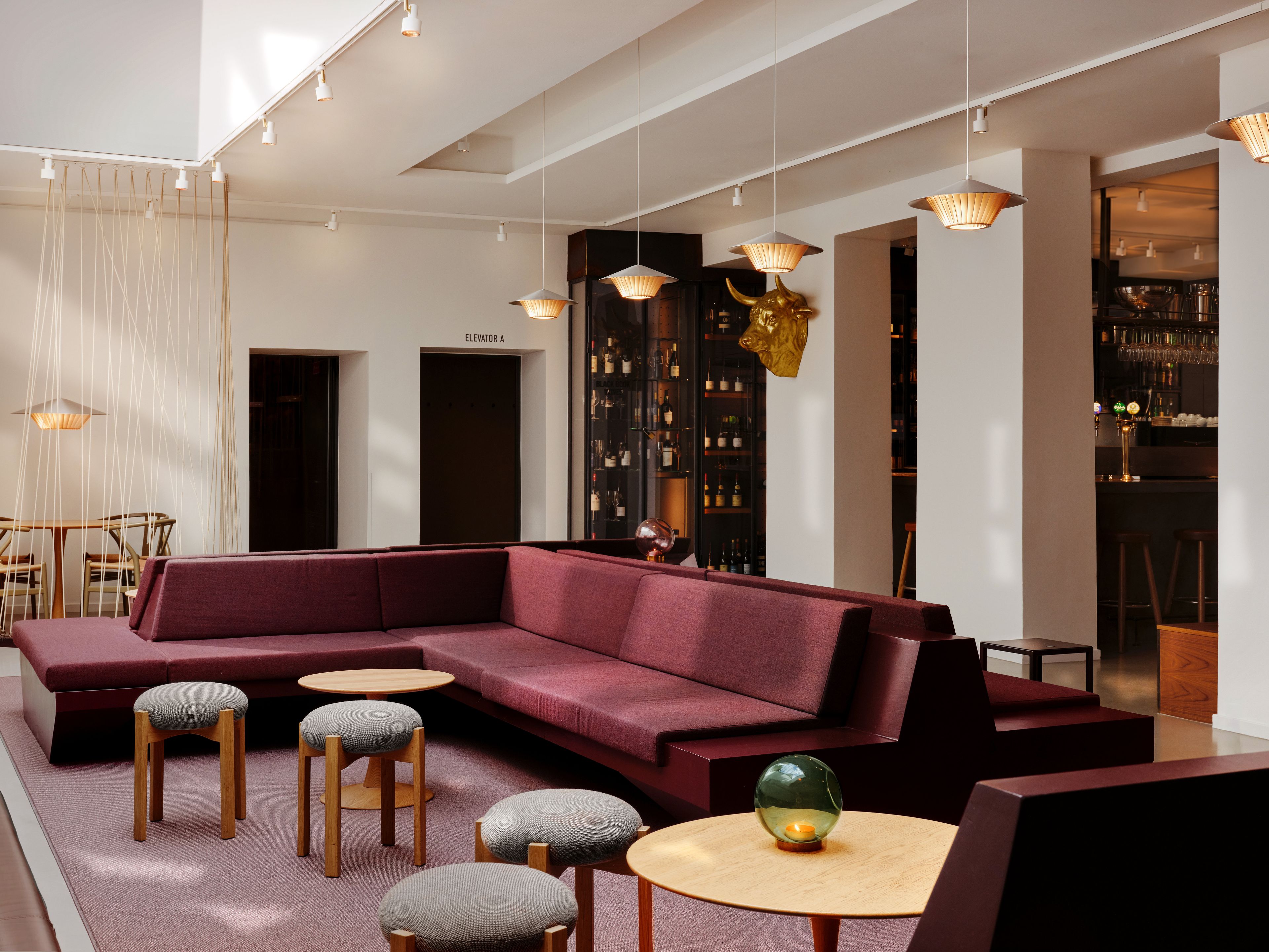 A modern lounge area with a sectional sofa, round tables, and bar seating.