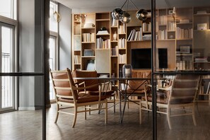 A modern library with bookshelves, leather chairs, and a glass table.