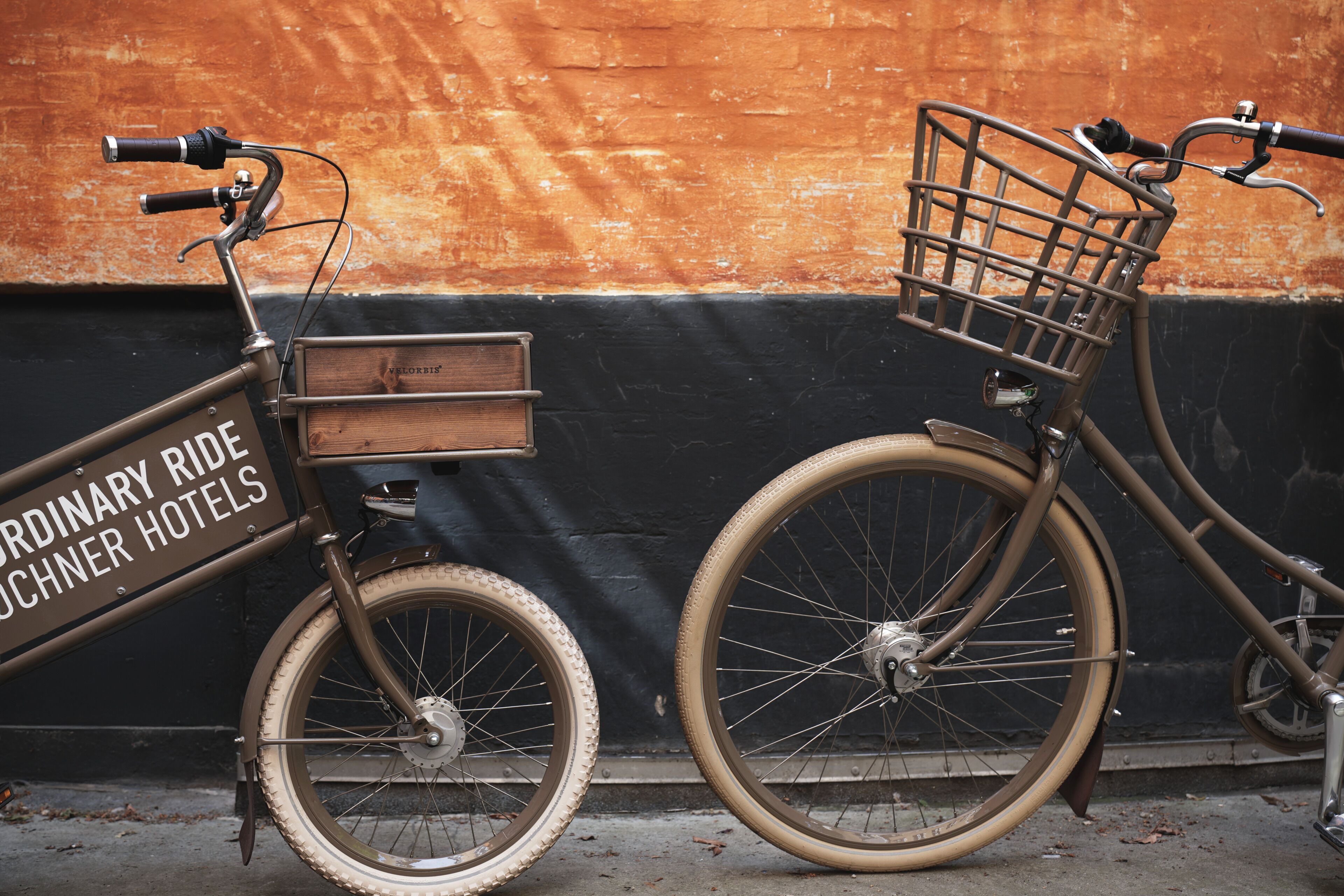 Un vélo avec un panier et une boîte en bois fixée au cadre, garé contre un mur.