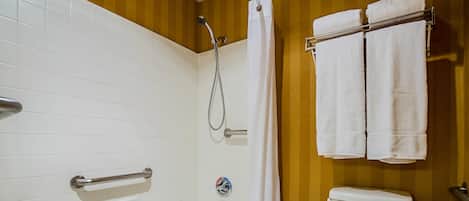 A bathroom with a bathtub, shower, toilet, and towel rack.
