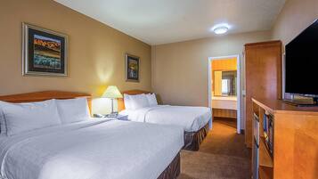 Una habitación de hotel con dos camas, televisión, escritorio y espejo.