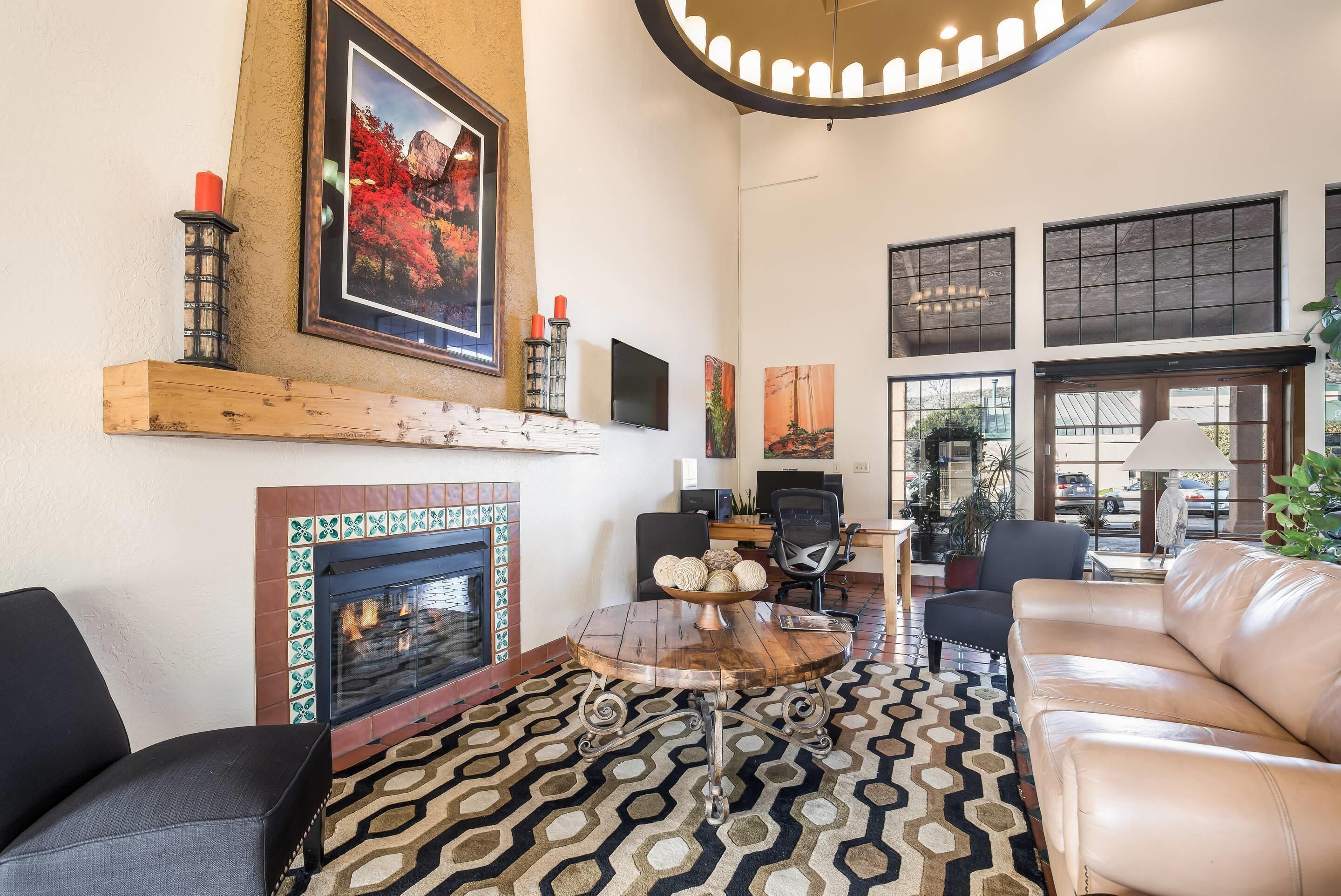 A living room with a fireplace, a round coffee table, leather sofas, and artwork on the walls.