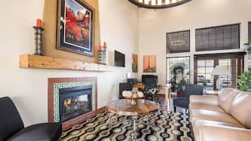 A living room with a fireplace, a round coffee table, leather sofas, and artwork on the walls.