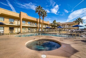 Un hotel con piscina, palmeras y un cielo azul despejado.