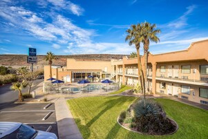 Un hotel con piscina, sombrillas exteriores y aparcamiento.