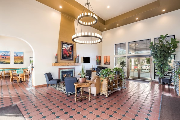 A spacious lobby with a fireplace, seating area, and large windows. - Clarion Suites St George - Convention Center Area (St. George)