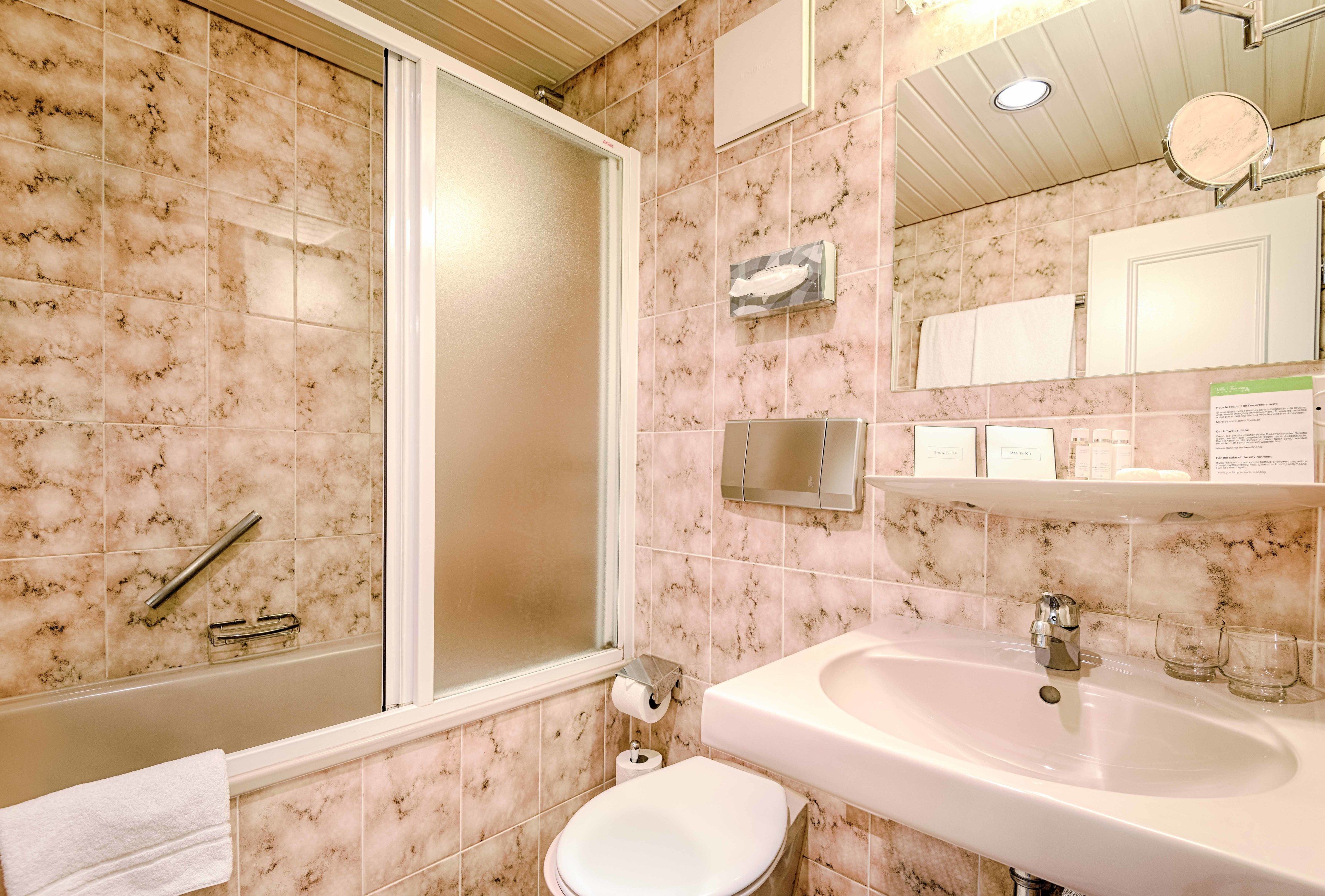 Un baño con bañera, inodoro, lavamanos y espejo.