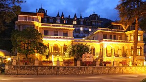 Een historisch hotel met meerdere verdiepingen, sierlijke architectuur en een bord waarop staat dat het een hotel is.