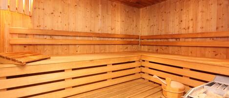 Un sauna en bois avec des bancs et un seau en bois.