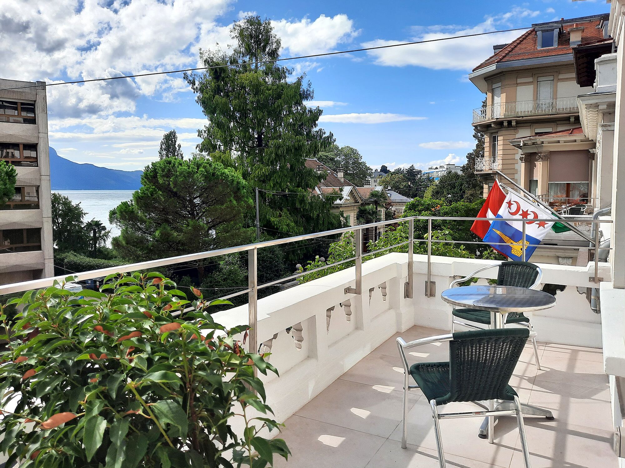Ein Balkon mit Meerblick, eine Flagge und ein Tisch mit Stühlen.