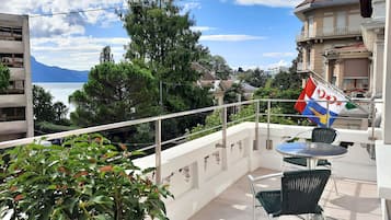 Ein Balkon mit Meerblick, eine Flagge und ein Tisch mit Stühlen.