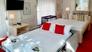 Habitación de hotel con dos camas, un televisor, un escritorio con teléfono y un espejo.