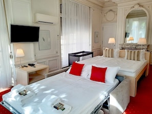 Habitación de hotel con dos camas, un televisor, un escritorio con teléfono y un espejo.