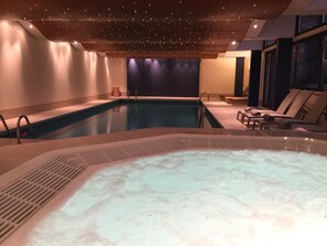 A swimming pool with a hot tub, lounge chairs, and a dark wall in the background. - Villa Toscane (Montreux)
