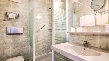 A modern bathroom with a glass-enclosed shower, a white sink, and a toilet.