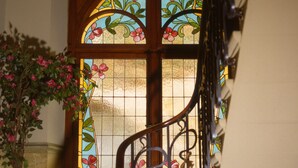 Una escalera con barandilla de hierro forjado que lleva a una puerta con vidrieras decoradas con motivos florales.
