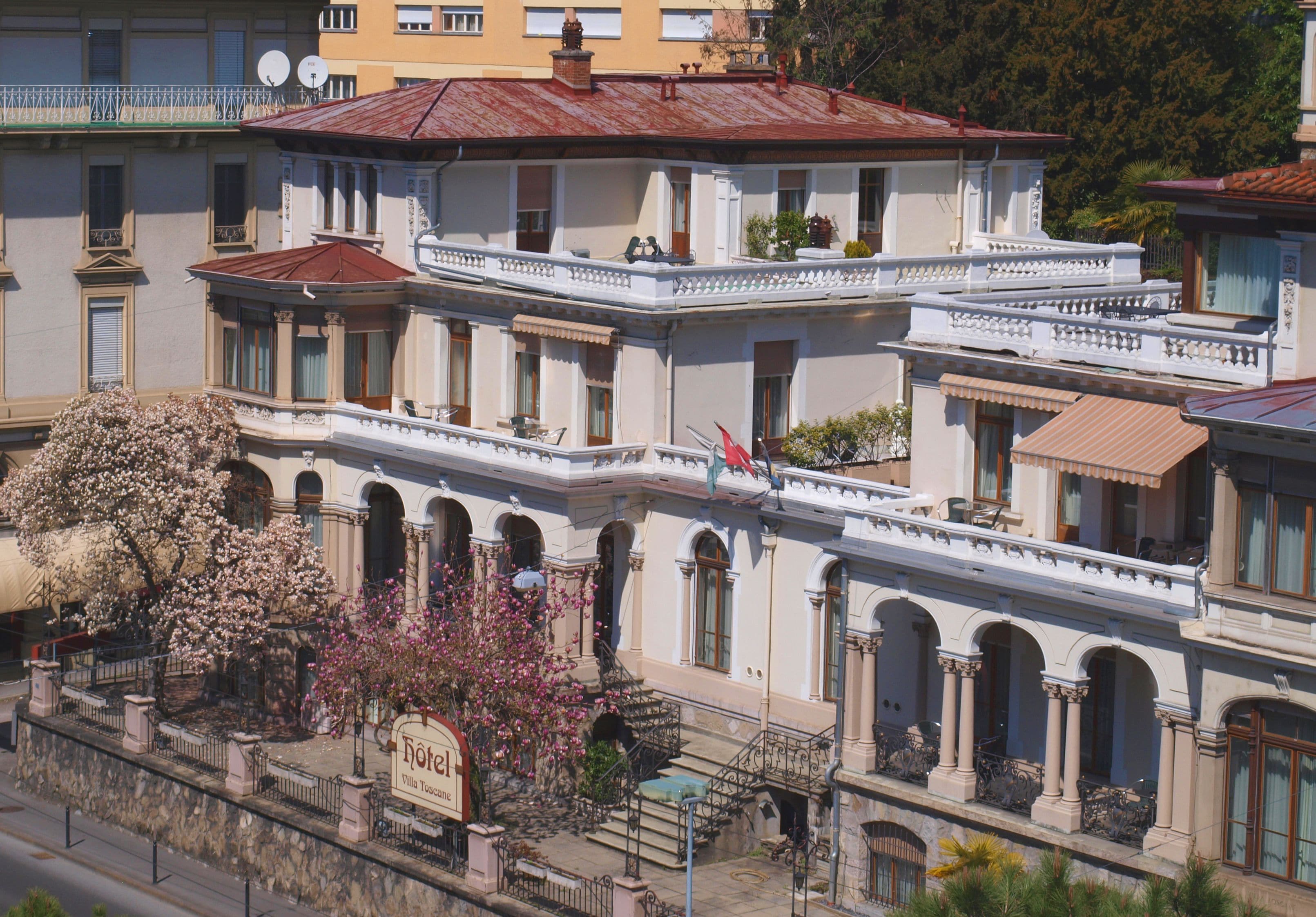 Un hotel de varios pisos con estilo arquitectónico clásico, que presenta balcones, ventanas en arco y fachada de piedra.