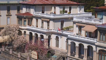 Un hôtel à plusieurs étages, de style architectural classique, doté de balcons, de fenêtres en arc de cercle et d’une façade en pierre.