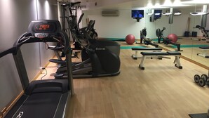 Un gimnasio con máquinas de cardio, un espejo grande y equipo de ejercicio.