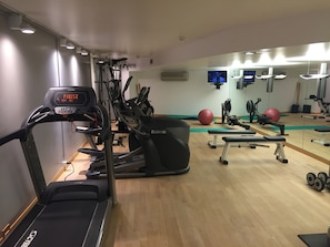 Un gimnasio con máquinas de cardio, un espejo grande y equipo de ejercicio.