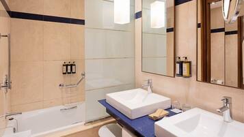 A modern bathroom with two sinks, a bathtub, and a shower.