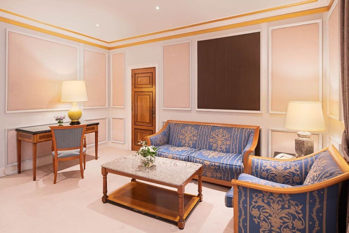 A room with a sofa set, a small table, a chair, and a lamp.
