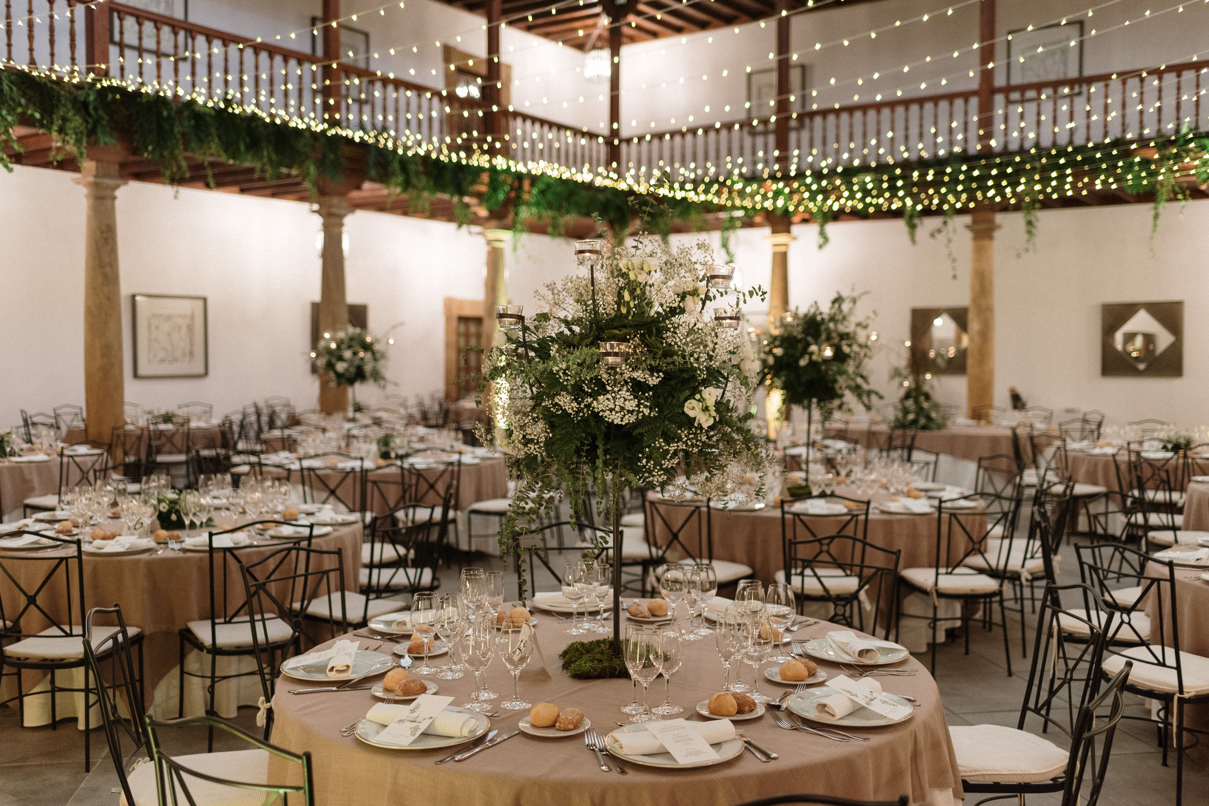 A banquet hall with round tables set for a formal event, featuring floral centerpieces and a warm, inviting atmosphere.