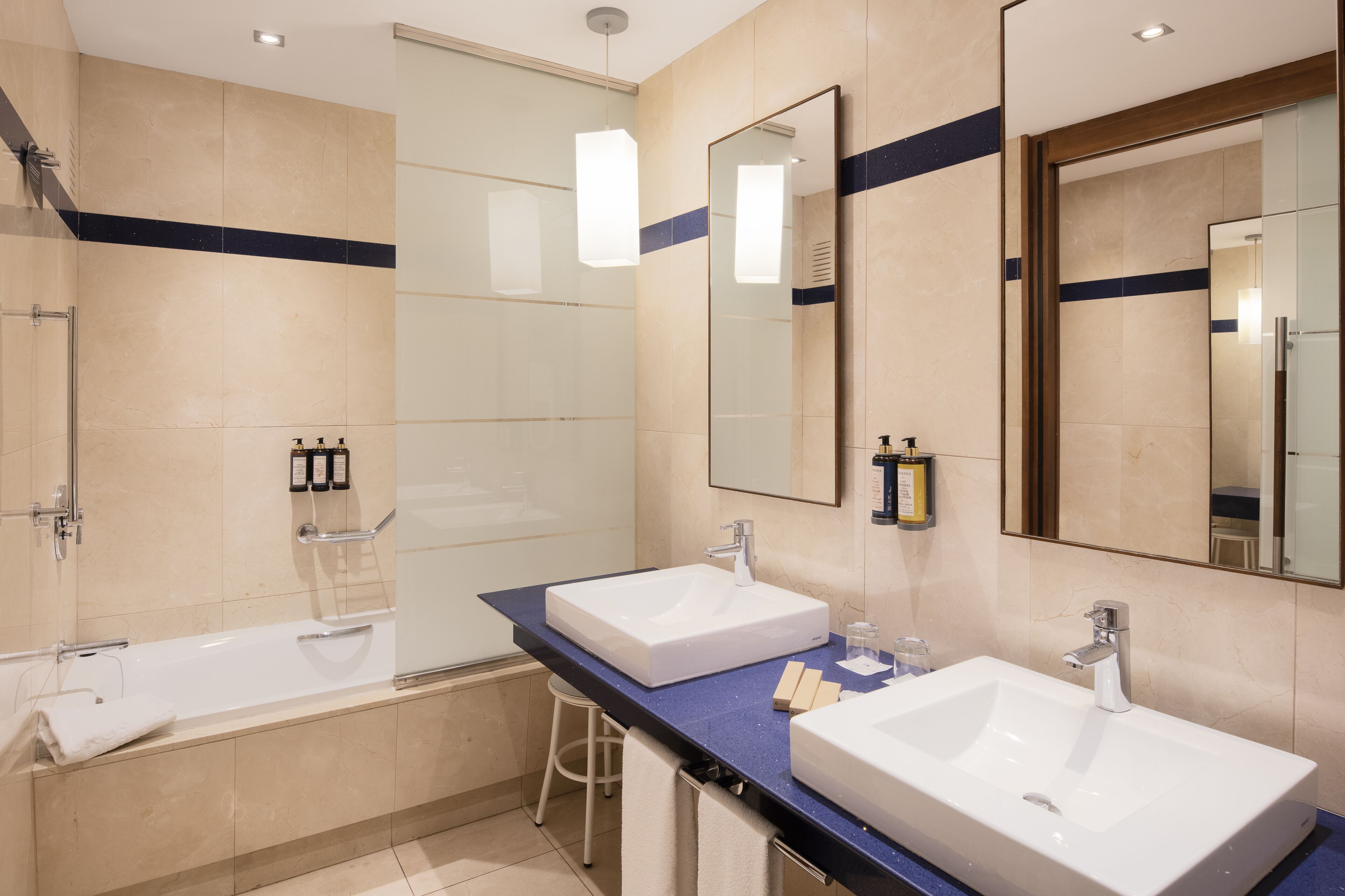 A modern bathroom with two sinks, a large mirror, and a walk-in shower.